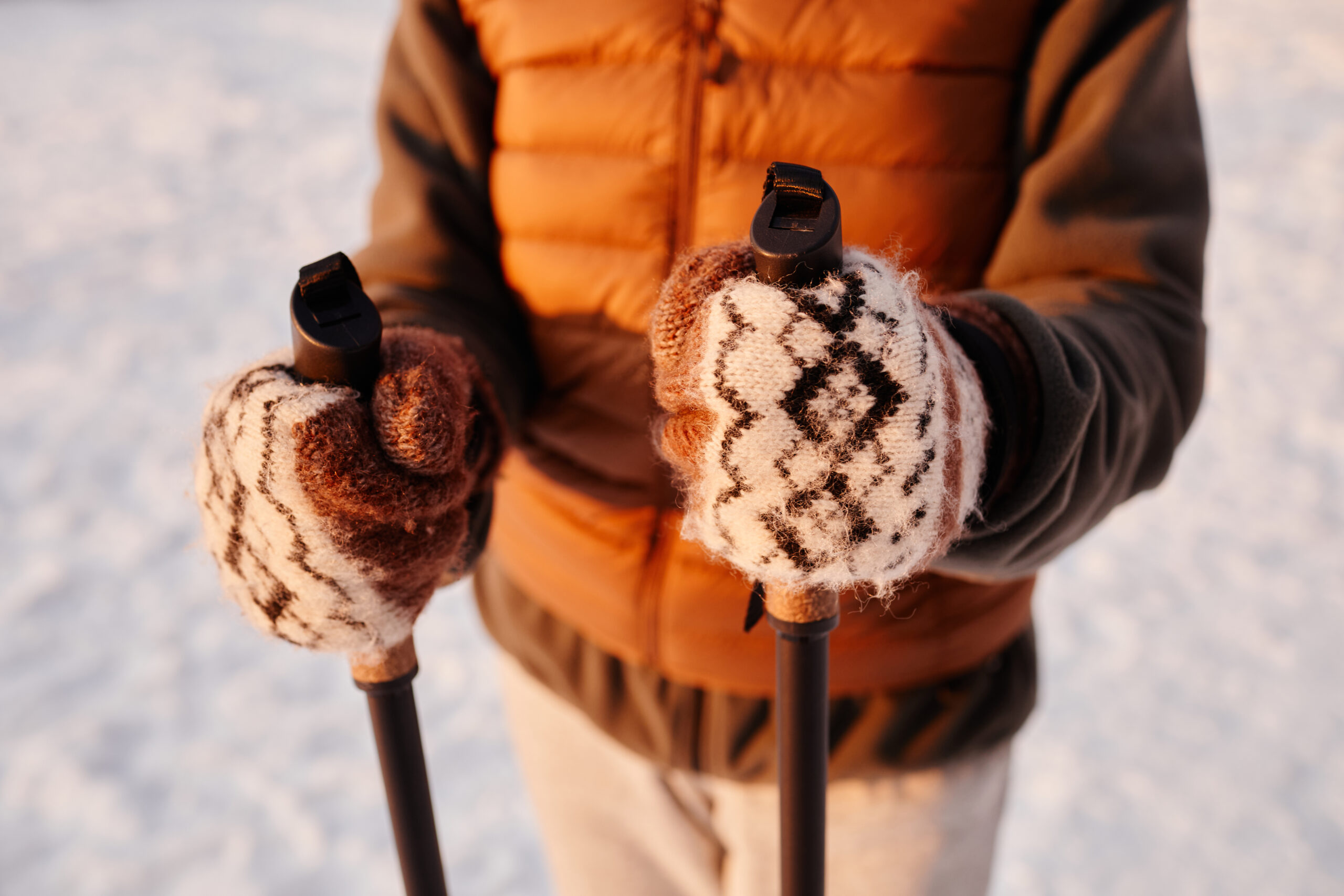 Close up of woman holding Nordic poles in winter with focus on wool mittens, copy space
